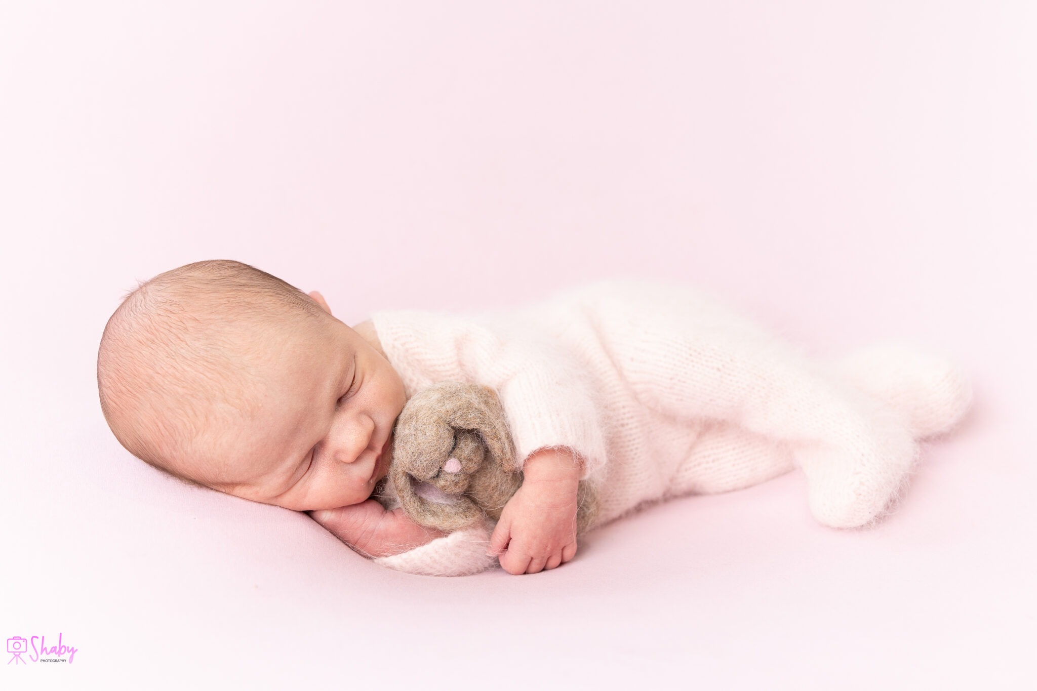 Newborn baby girl Nora sleeping peacefully with a gentle smile, during a professional photography session in Ireland.