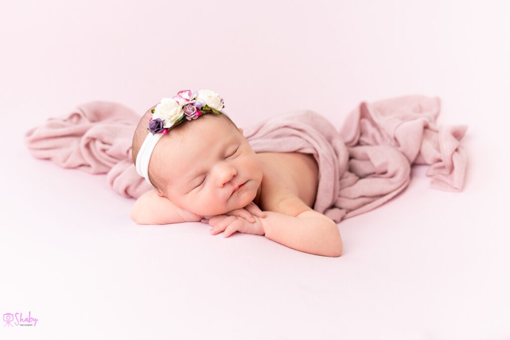 Newborn baby girl Nora sleeping peacefully with a gentle smile, during a professional photography session in Ireland.