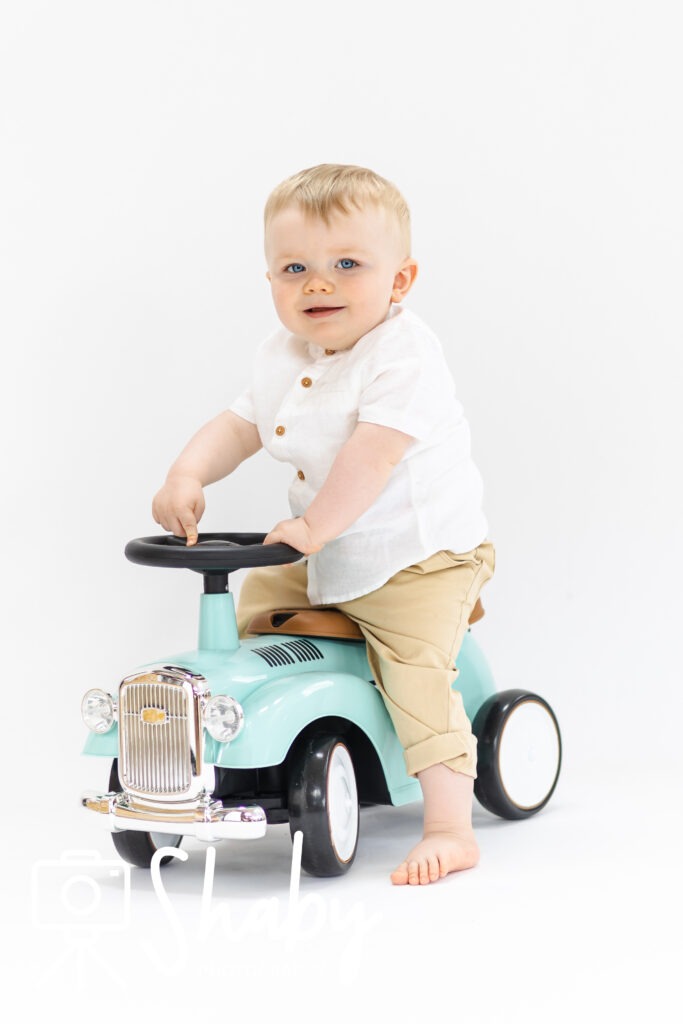 Photo from baby photography photoshoot of a beautiful baby boy, posing on a toy scooter photography prop, by www.shaby.ie