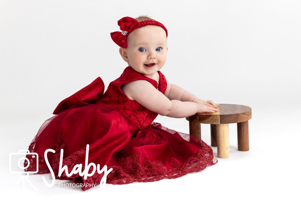 Close-up of toddler Nina posing in a bright red dress for a playful photography session